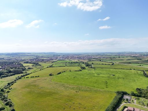 A drone image of green fields and clear blue skies of England with a few clouds