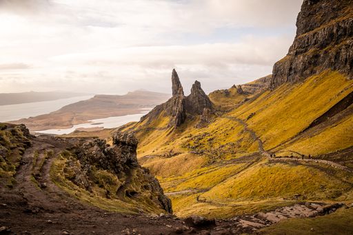 A scenic view of Old Man of Storr on the Isle of Skye, Scotland, with rugged landscape and walking trail on a clear day