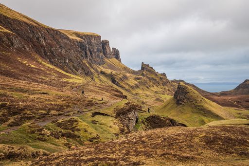 Scenic view of the Quiraing landslip on the Isle of Skye with hikers on a trail under a cloudy sky