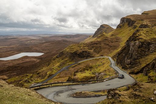 A scenic view of a winding road through the rugged landscape of the Quiraing, Isle of Skye, Scotland