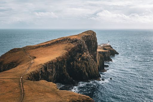 A stunning view of Neist Point Lighthouse on the Isle of Skye, Scotland, with dramatic cliffs and the ocean