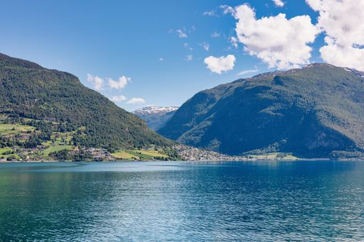 A stunning view of the serene Hardangerfjord surrounded by mountains under a clear blue sky in Norway