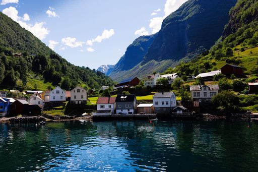 A scenic view of a small town by the fjord in Norway surrounded by mountains and clear blue sky