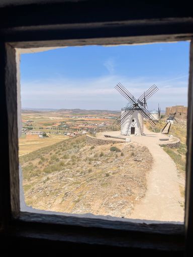 A view of traditional windmills and the countryside through a window frame in Consuegra, Spain