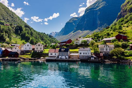 A scenic view of a small town by the fjord in Norway surrounded by mountains and clear blue sky