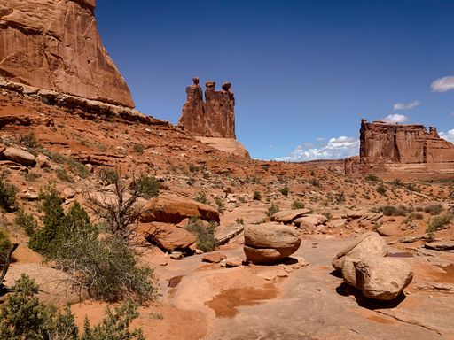 A scenic view of the Arches National Park with red rock formations under a clear blue sky