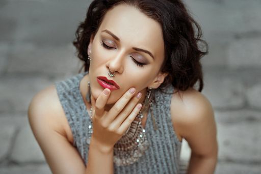 A portrait of a sexy Caucasian woman with a septum piercing with her eyes closed