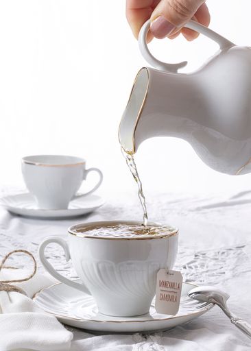 A vertical shot of a person pouring hot water to a teacup for a tea party
