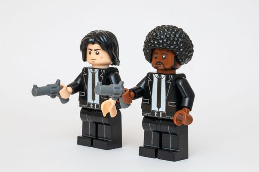 Two Lego minifigures dressed in a black suit holding a weapon