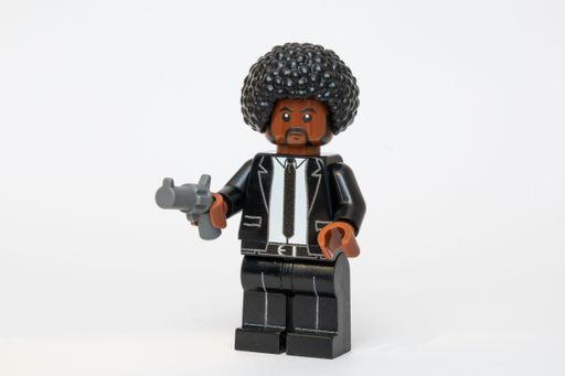 A Lego minifigure dressed in a black suit holding a weapon