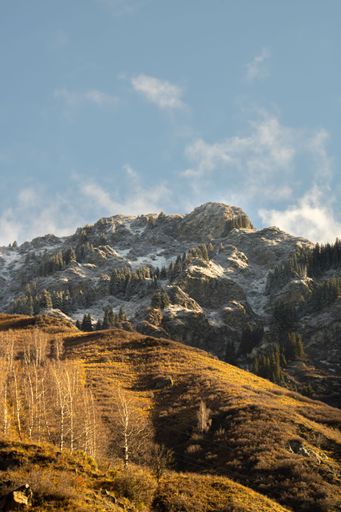 A vertical shot of a snow-capped mountain range on a sunny day in Yaponskaya Doroga hiking area in Almaty region, Kazakhstan
