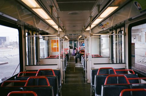 Interior view of an empty public transit bus with red and blue seats and large windows.