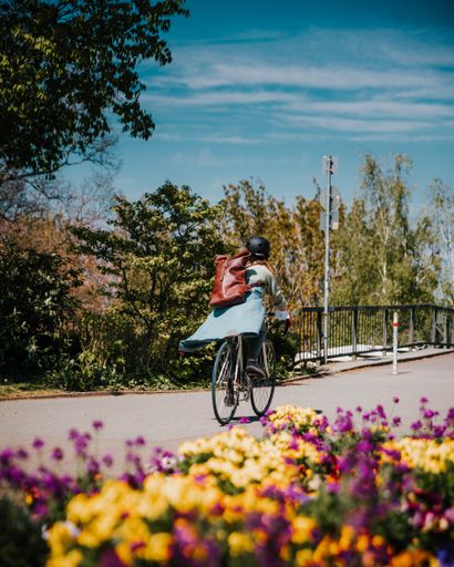 A vertical shot of a person riding a bicycle in a park covered in flowers in Mainz, Germany