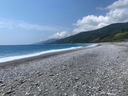 A scenic view of a pebble beach with mountains in the background. Taiwan, Taitung