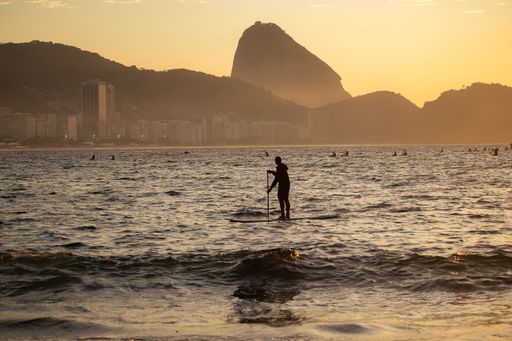 A person paddleboarding during sunset with Sugarloaf Mountain in the background, Rio de Janeiro