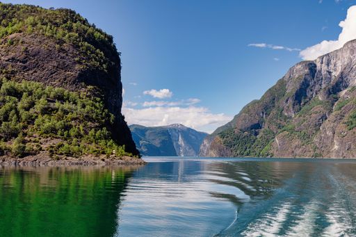 A stunning view of a Norwegian fjord with clear waters and majestic mountains under a bright blue sky