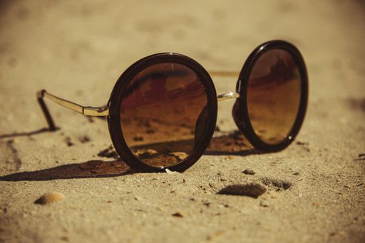 A closeup shot of sunglasses on the sand