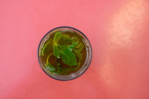 Close up view of a Top view of a Glass of moroccan tea with mint plant with copy space in red background