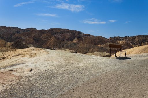 A solitary bench overlooking the rugged terrain of Death Valley National Park under a clear blue sky.