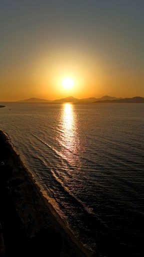 A stunning sunset over the ocean with a view of distant mountains and a serene beach in Kos Island