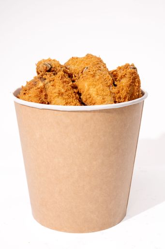 A bucket filled with crispy fried chicken pieces on a plain white background