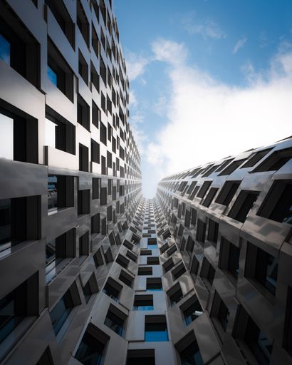 A low-angle shot of modern high-rise buildings with reflective windows against a blue sky with clouds