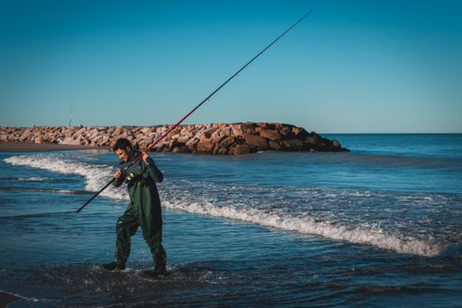A young Argentine man trying his luck at fishing for the first time at the sea during sunset