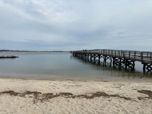 A dock and the sandy beach in Yorktown, Virginia under the cloudy sky