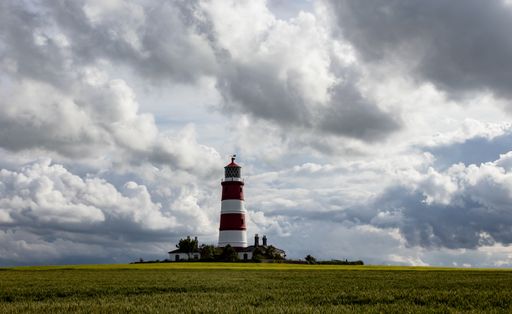 A beautiful view of Happisburgh Lighthouse in UK under cloudy sky with green lawn