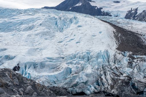 A stunning view of a glacier with rugged terrain and snow-capped mountains in the background