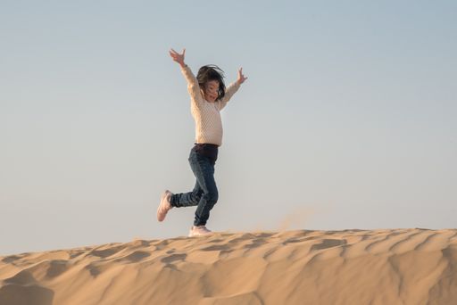 An Asian child running in the desert under the sky
