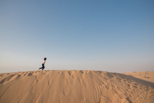 An Asian child running in the desert under the sky