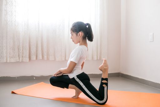 A young athletic Mexican girl practicing yoga in her room on an orange mat