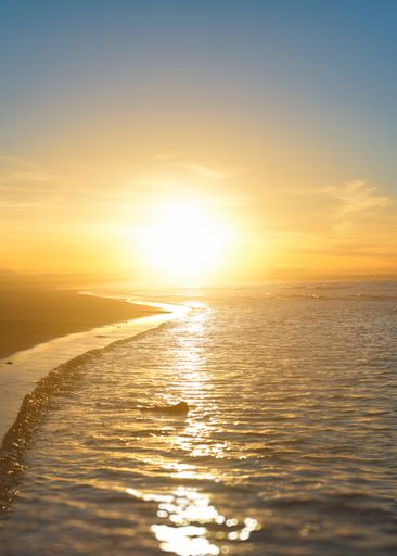 A beautiful sunset over a calm beach with golden reflections on the water.