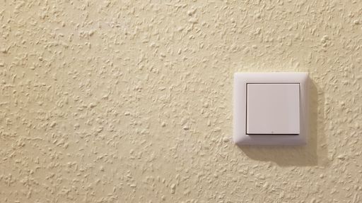 White light switch on the wall on yellow background