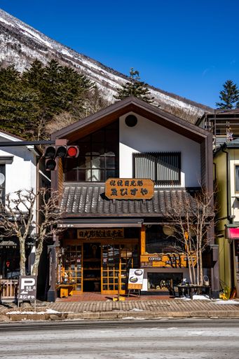 Traditional Japanese shop with mountain backdrop in Nikko, Japan on a clear day.
