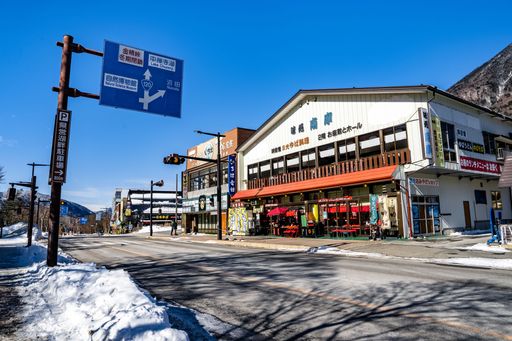 A street view of a Japanese town with buildings, signage, and a clear blue sky on a sunny winter day.