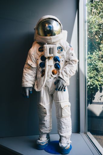 A full view of an astronaut suit displayed in a museum next to a window with natural light