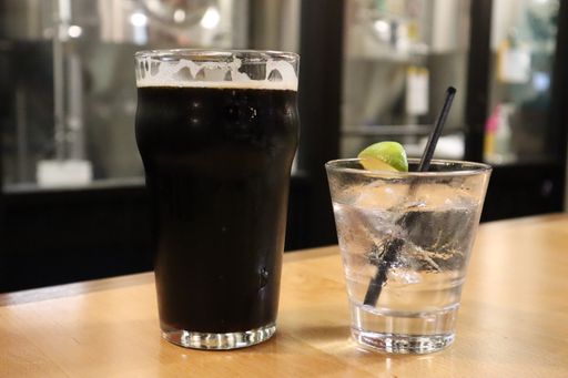 A closeup shot of dark beer and a gin cocktail with lime garnish at a brewery in Utah, USA