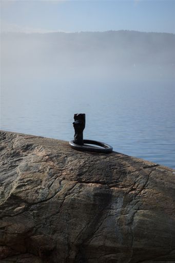 A vertical shot of a bollard on a wooden surface for boats surrounded by the s