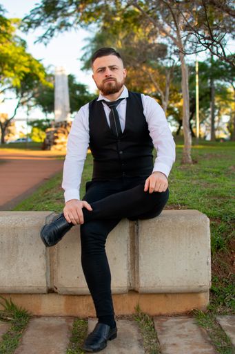 An attractive Hispanic male in an elegant suit posing at camera in the park