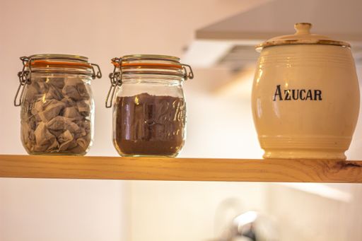 A selective focus shot of jars of mushroom, coffee, and a keg with a "Sugar" inscription on a shelf