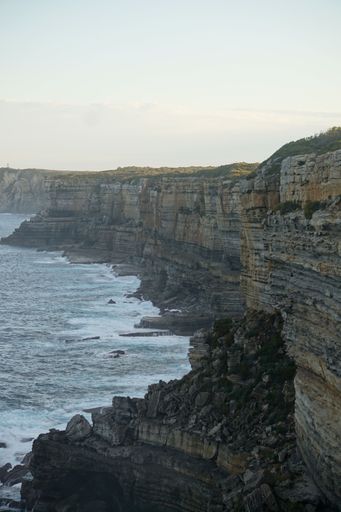 A scenic view of rugged coastal cliffs with waves crashing against the rocks