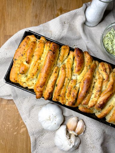 A vertical shot of freshly baked garlic bread on a wooden surface