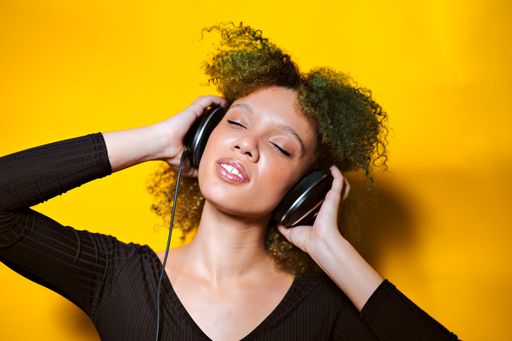 A closeup shot of an African American woman listening to music with her headphones
