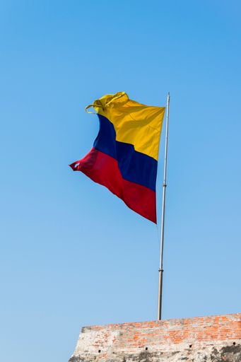 A Colombian flag is streaming in the wind over the weathered walls of the fortress of Castillo San Felipe de Barajas in Cartagena de Indias, Colombia.