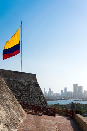 A Colombian flag is streaming in the wind over the weathered walls of the fortress of Castillo San Felipe de Barajas in Cartagena de Indias, Colombia.