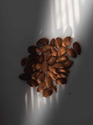 A vertical closeup shot of fresh almonds on a grey background