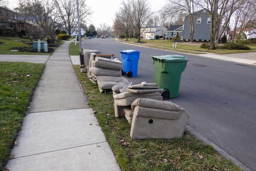 Old furniture on the sidewalk near the trashcans in a neighborhood in the daytime