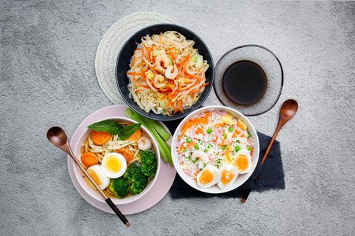 A top view of different dishes with noodles, eggs, and vegetables in bowls